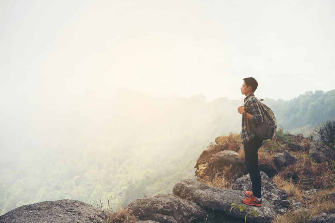 a male watching the sky near a cliff